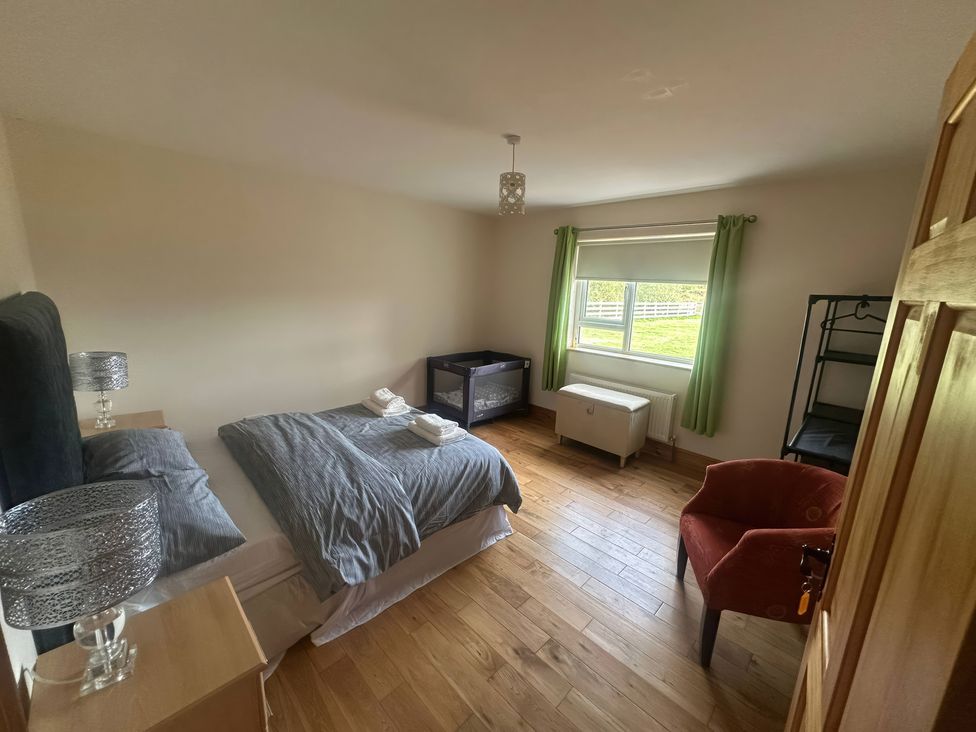 A bedroom with a bed and armchair at Storey and Half House Near Annagry, County Donegal