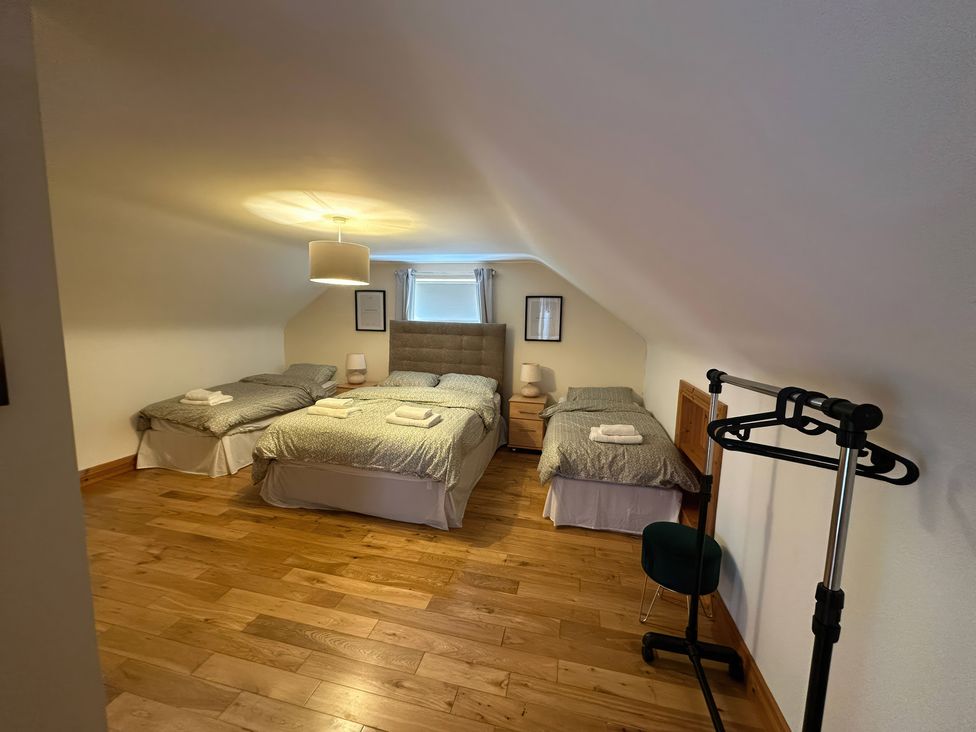 A bedroom with three beds and a clothes rack at Storey and Half House near Annagry, County Donegal