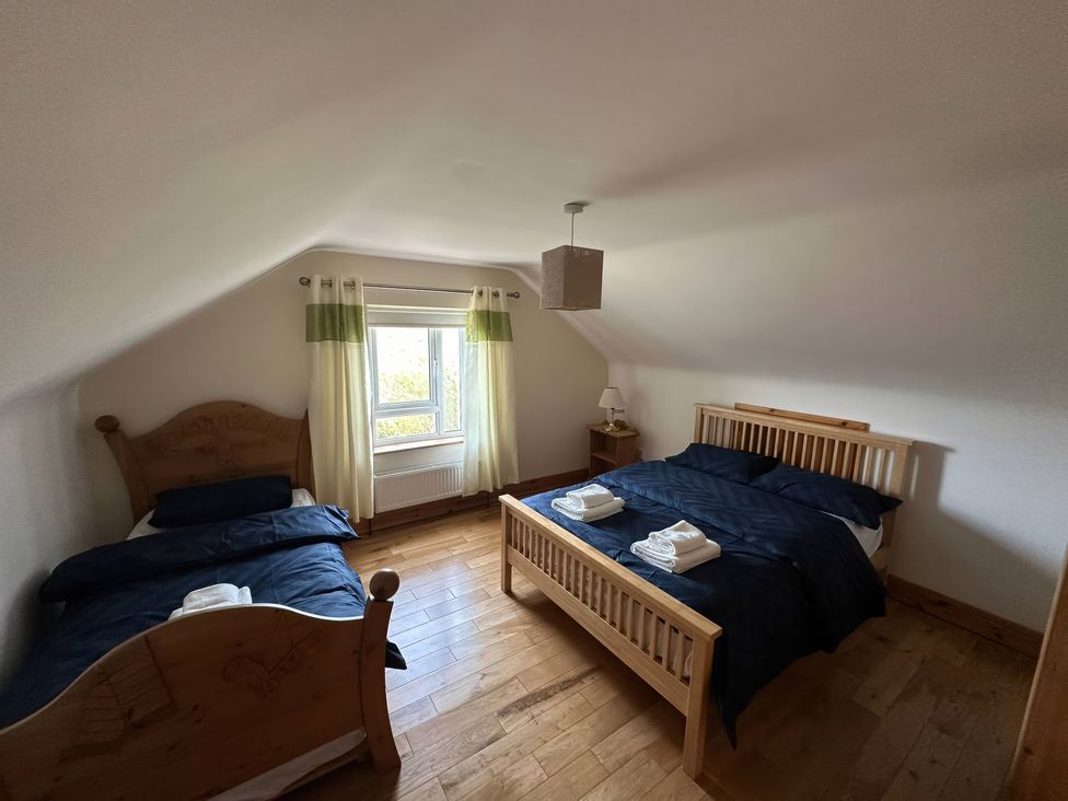A bedroom with two beds and a window at Storey and Half House near Annagry, County Donegal