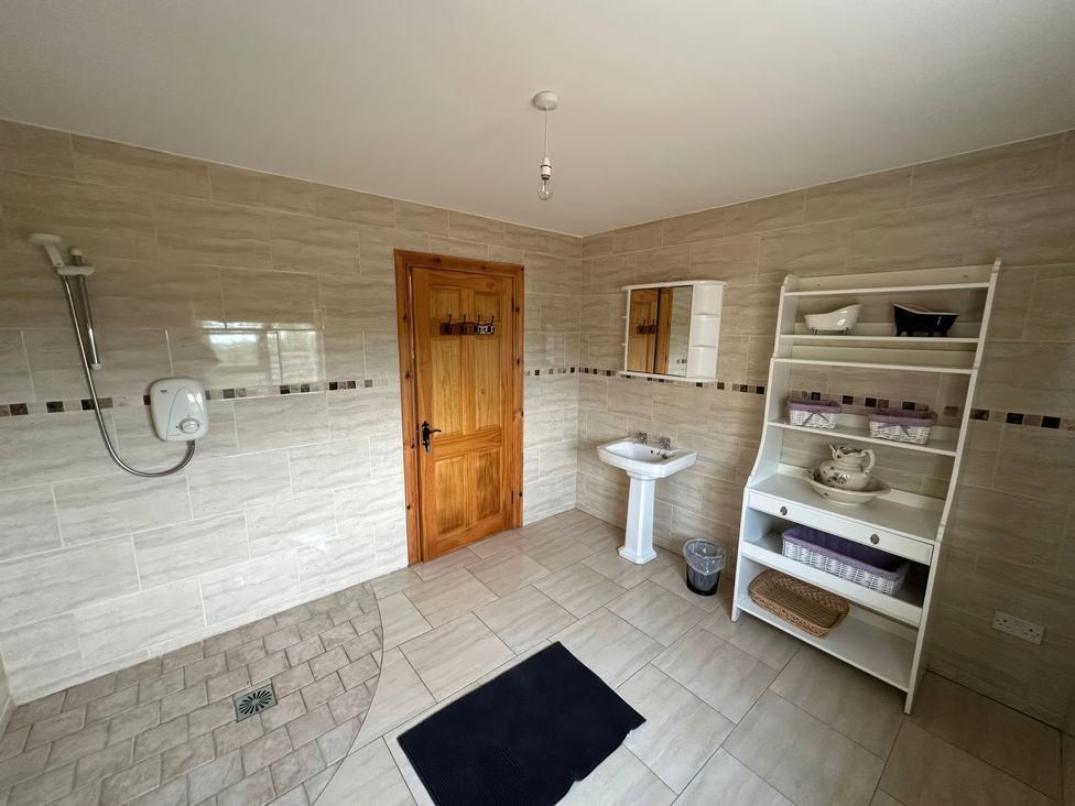 A bathroom with a shower and washbasin at Storey and Half House Near Annagry, County Donegal