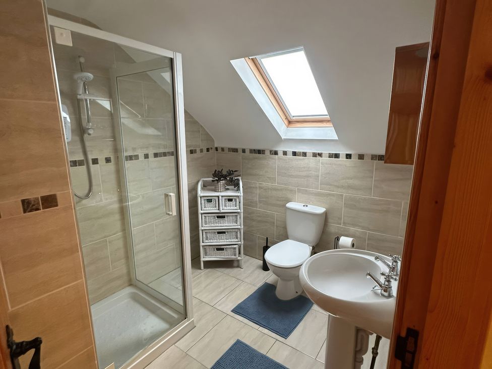 A bathroom with a shower, toilet, and sink at Storey and Half House Near Annagry, County Donegal