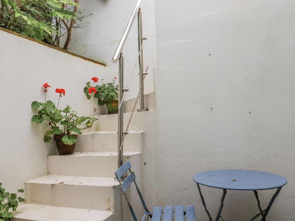 A staircase with plants and a table and chair at Cove Retreat in Penzance