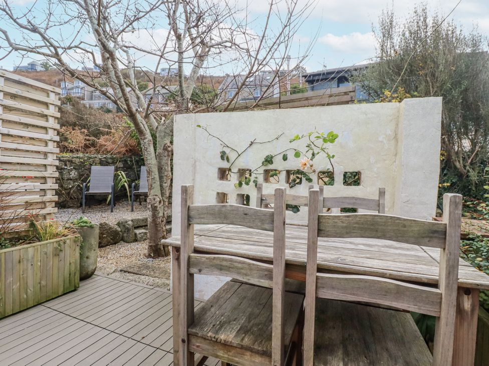 A garden with a wooden table and chairs at Cove Retreat in Penzance