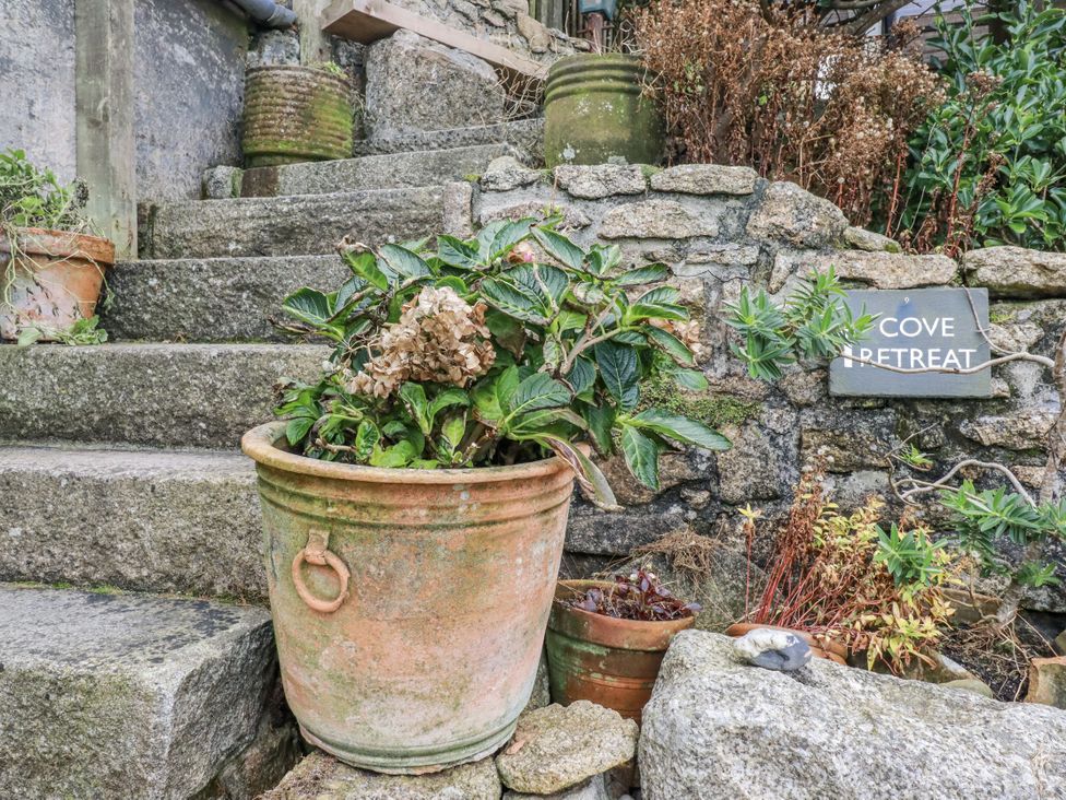 A garden area with a plant pot and stone steps at Cove Retreat in Penzance