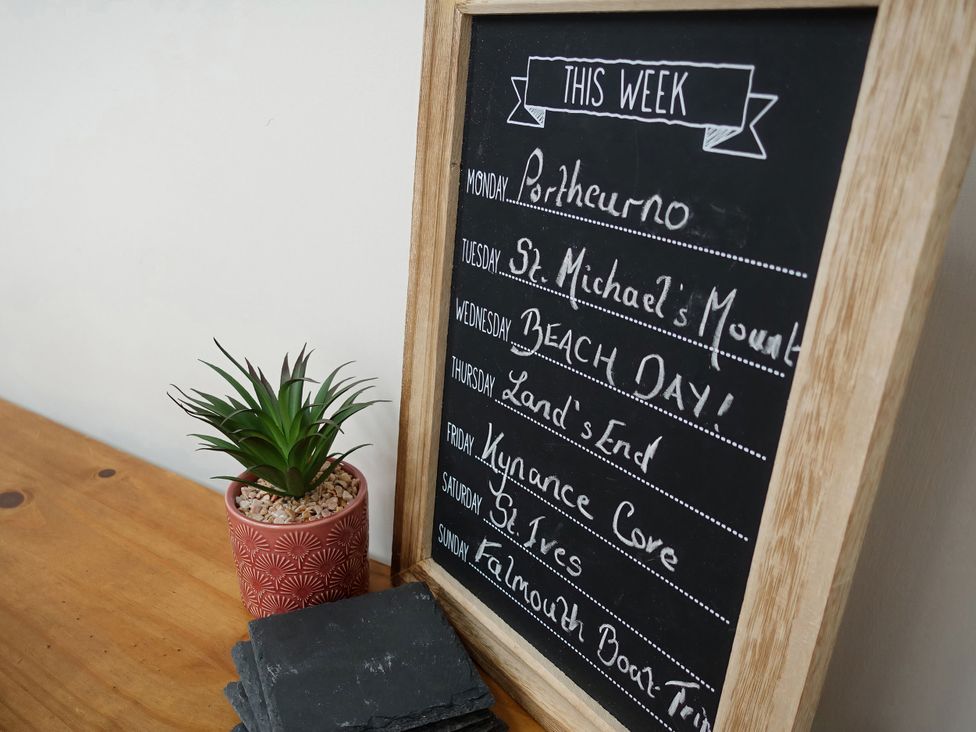 A chalkboard with a weekly schedule and a plant at Cove Retreat in Sennen Cove