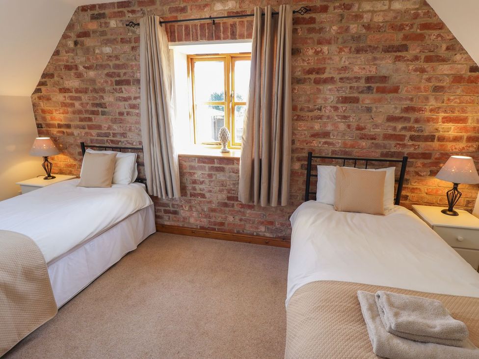 A bedroom with two single beds and a window at The Granary in Louth