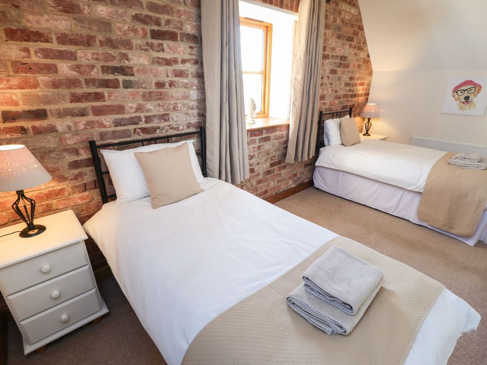 A bedroom with two beds and a bedside table at The Granary in Louth