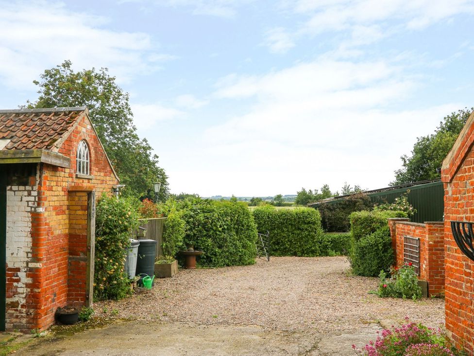 An outdoor area with a gravel driveway and surrounding hedges at Barn Owl in Louth