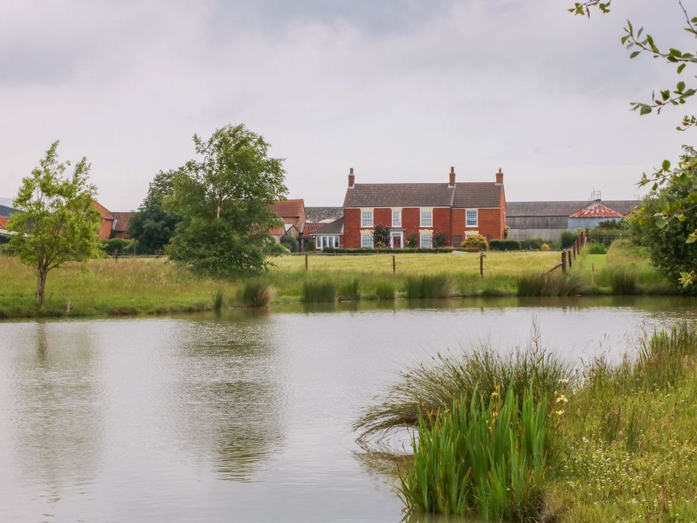 A house near a pond with grass and trees at Barn Owl in Louth