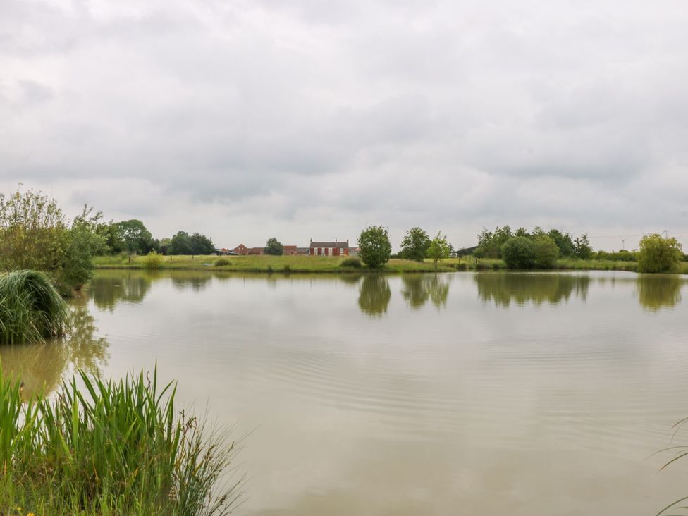 A pond with reflection and trees at Barn Owl in Louth
