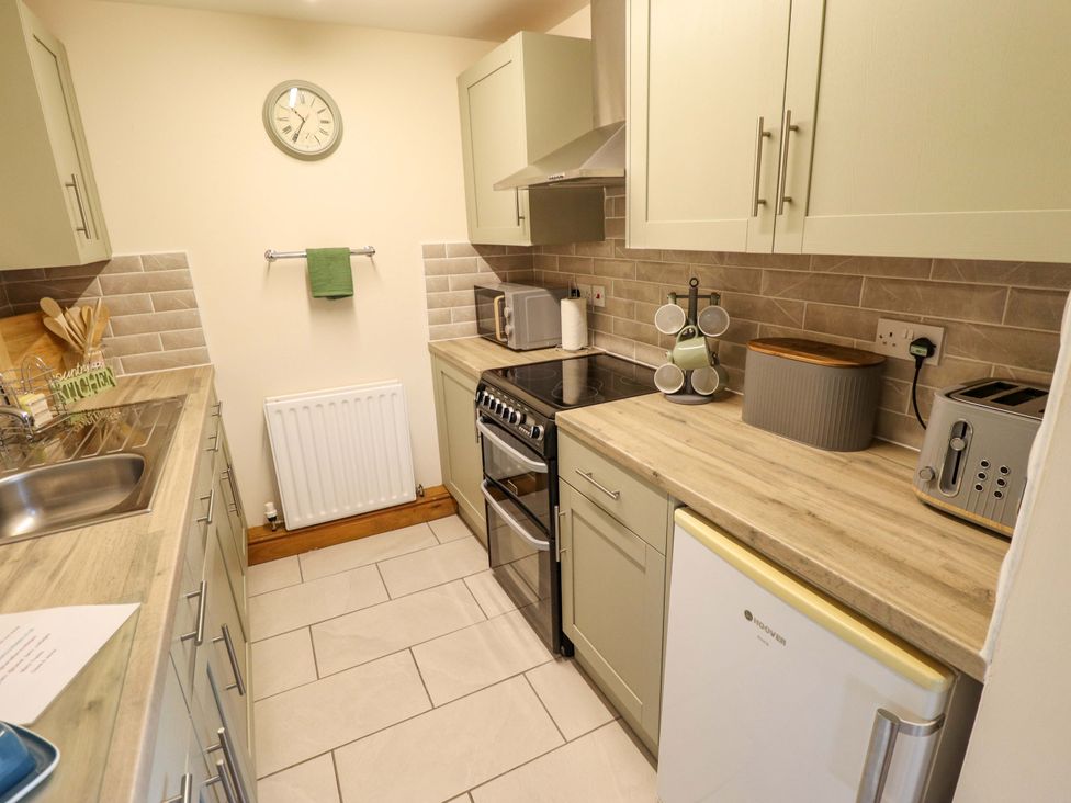 A kitchen with a sink, cooker, and fridge at Barn Owl near Louth