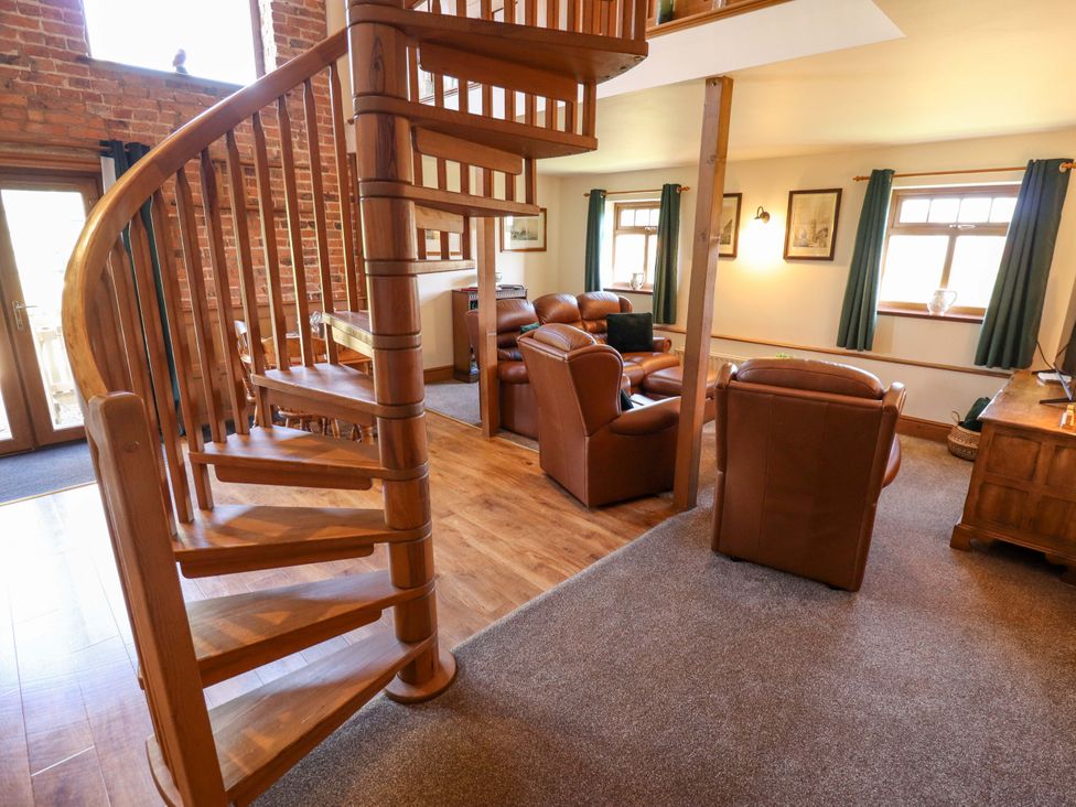 A living room with a spiral staircase and seating at Barn Owl near Louth