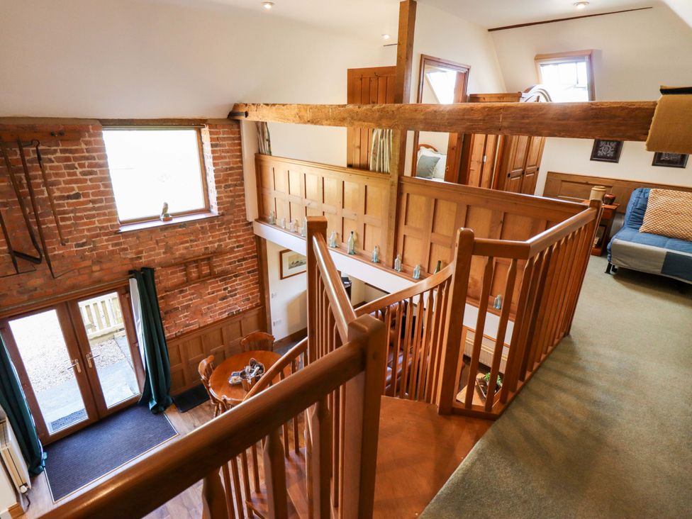 A hallway with a wooden staircase and railing at Barn Owl near Louth