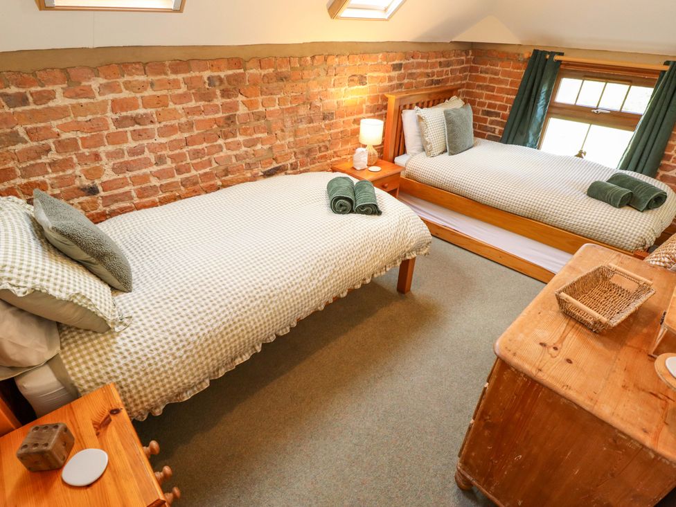 A bedroom with two beds and a wooden cabinet at Barn Owl near Louth