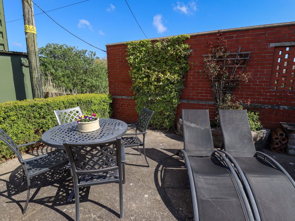 An outdoor area with a table, chairs, and sun loungers at Barn Owl near Louth