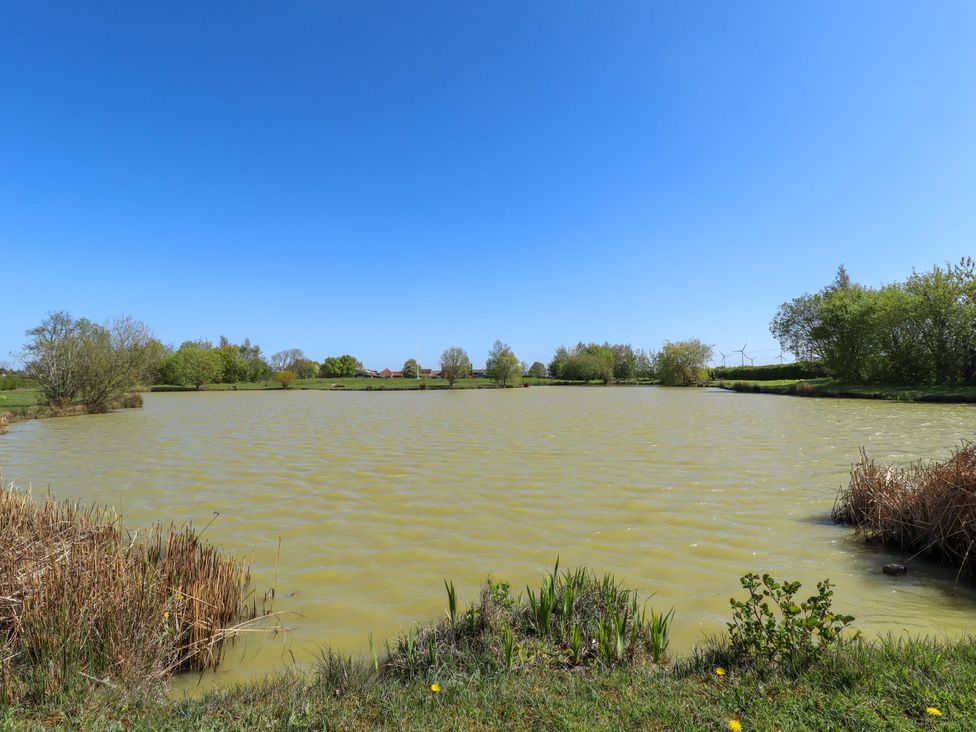A pond surrounded by grass and trees at Barn Owl near Louth
