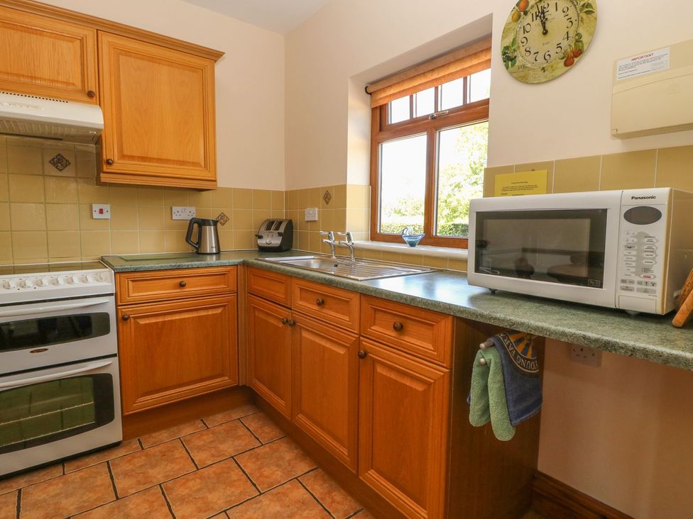 A kitchen with cabinets, sink, microwave, and kettle at Kingfisher in Louth