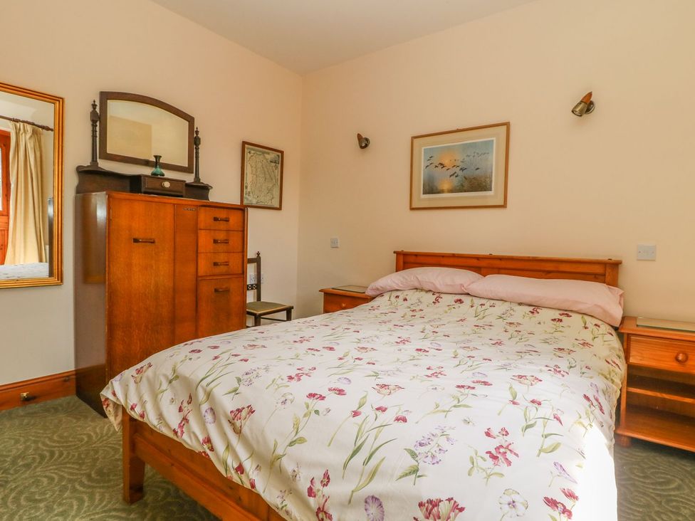 A bedroom with a bed and wooden furniture at Kingfisher in Louth