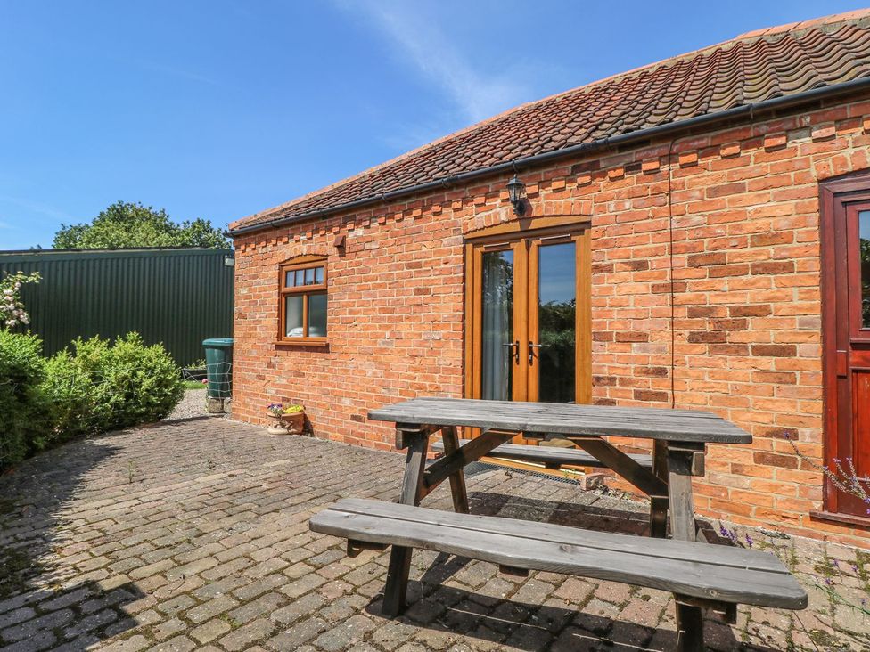 An outdoor area with a table and brick wall at Kingfisher in Louth