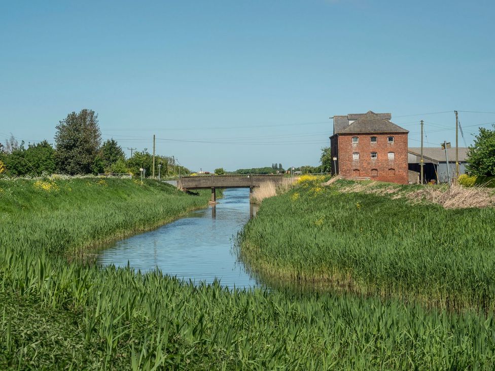 A waterway with a bridge and a building at Kingfisher in Louth