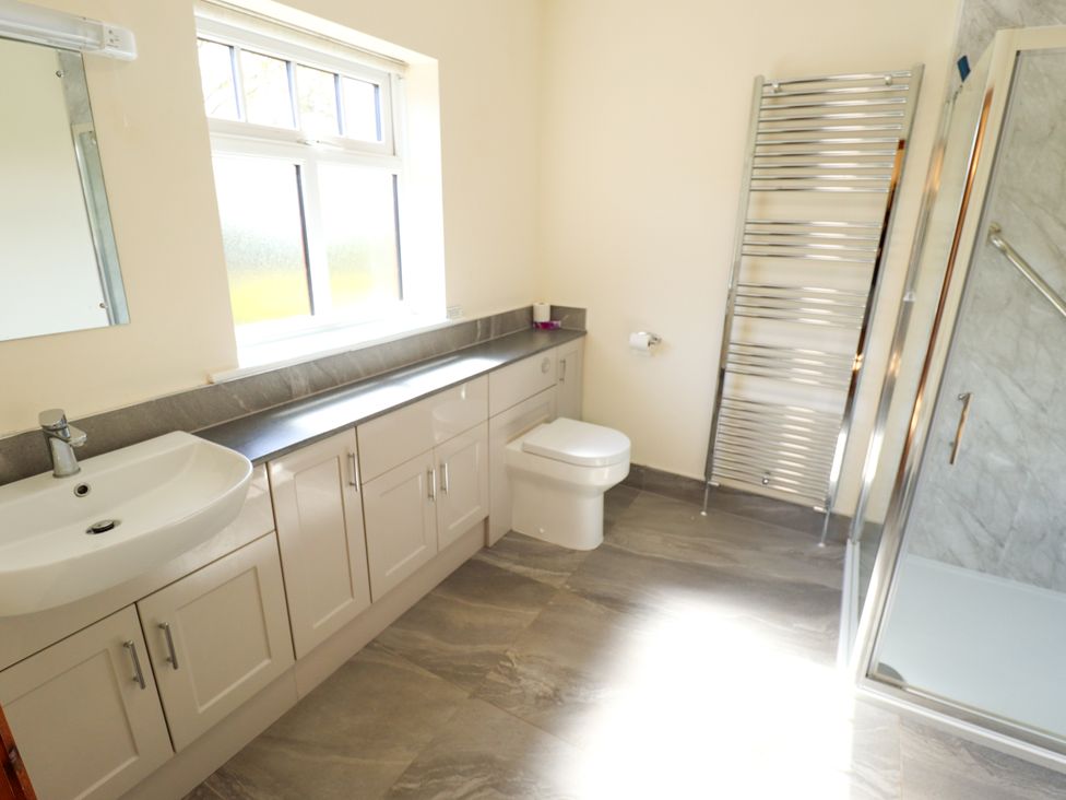A bathroom with a sink, toilet, towel rack, and shower at Kingfisher Near Louth