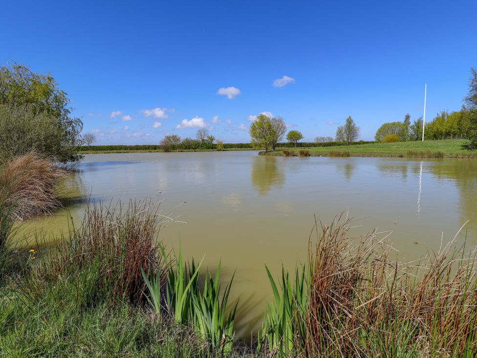 A lake surrounded by grass and trees at Kingfisher near Louth