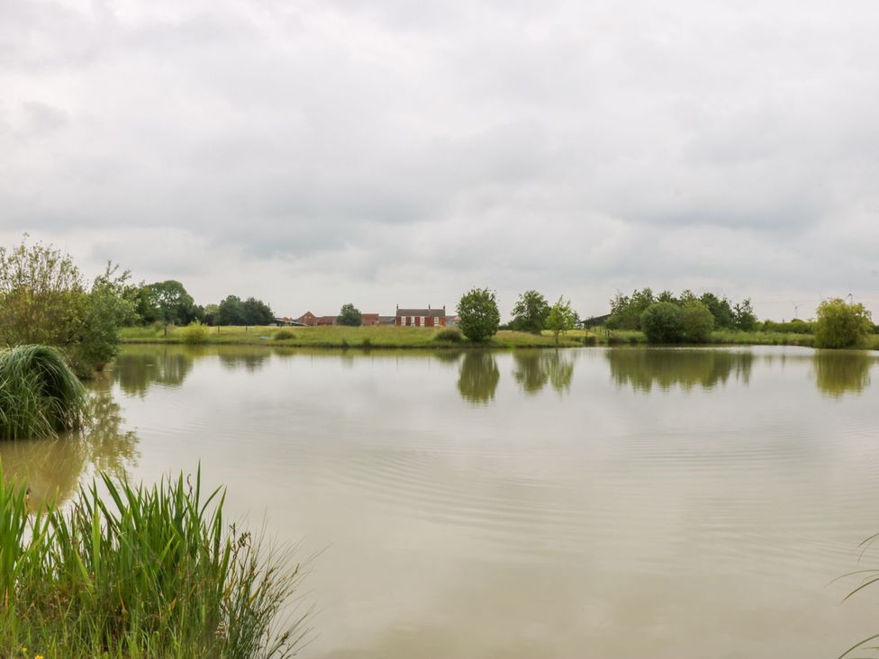 A lake with trees and buildings nearby at Ticklepenny in Louth