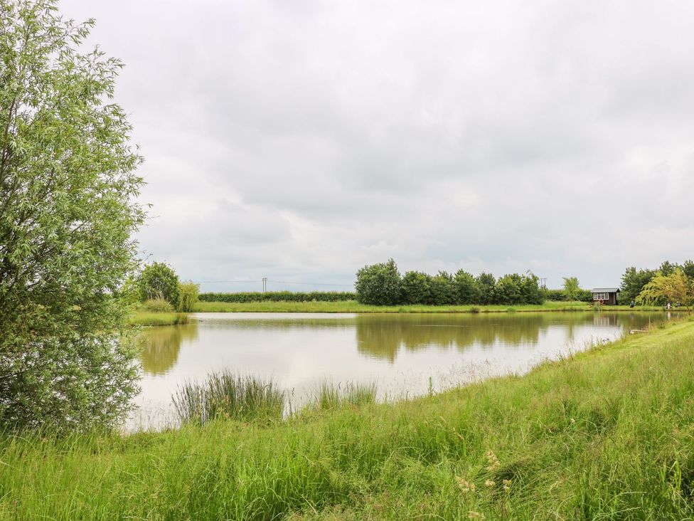 A lake surrounded by grass and trees at Ticklepenny in Louth