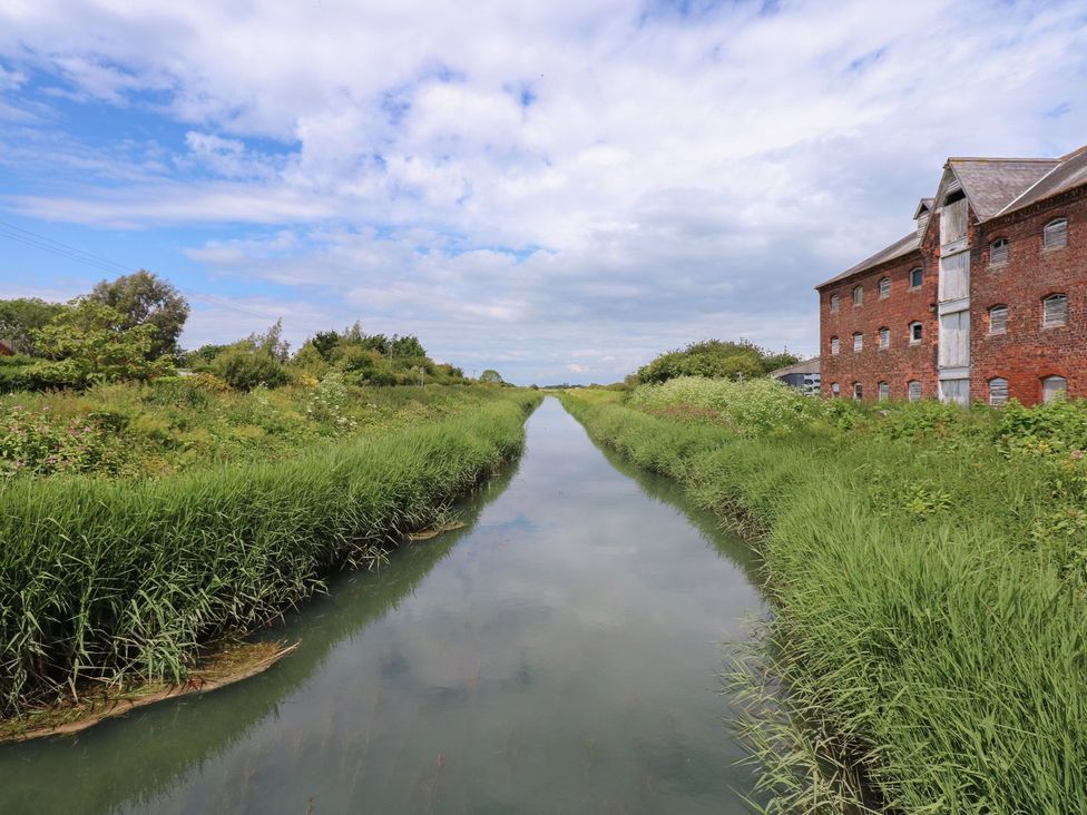 A water canal with grass and buildings at Ticklepenny in Louth