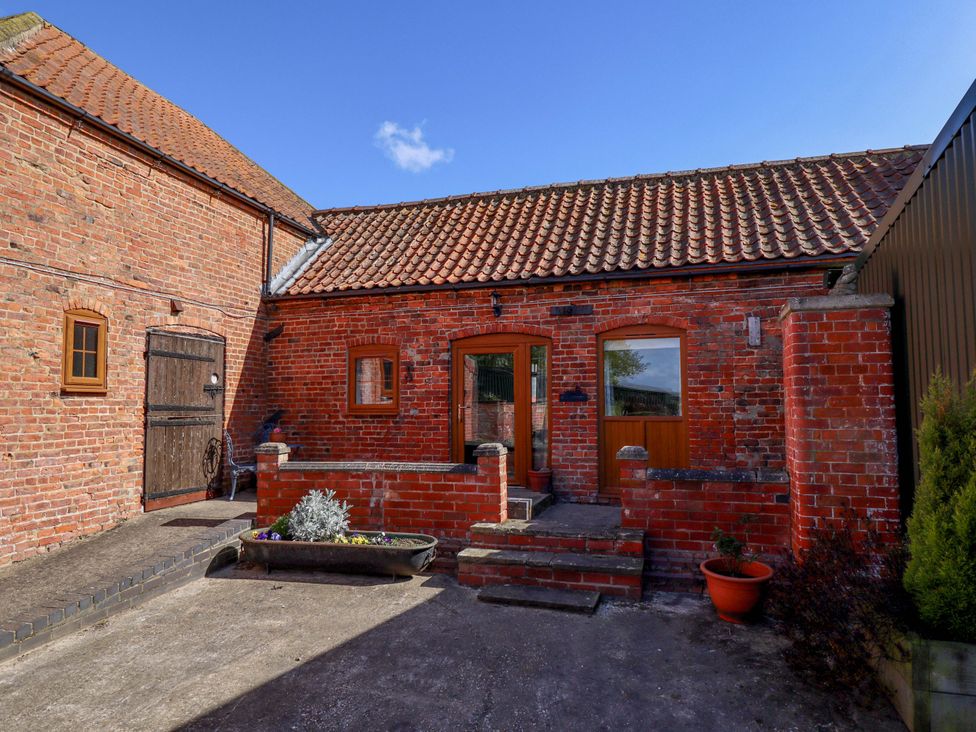 An outdoor view of a brick structure with a wooden door at Ticklepenny in Louth