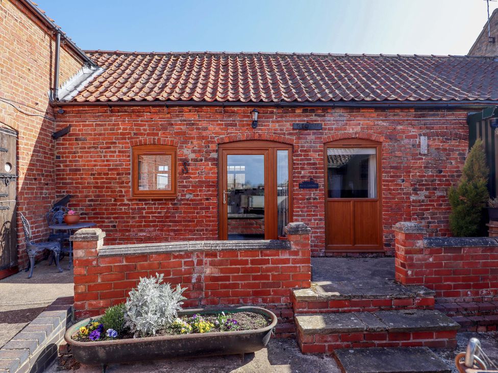 An outdoor view of a brick building with a front door and a plant pot at Ticklepenny in Louth