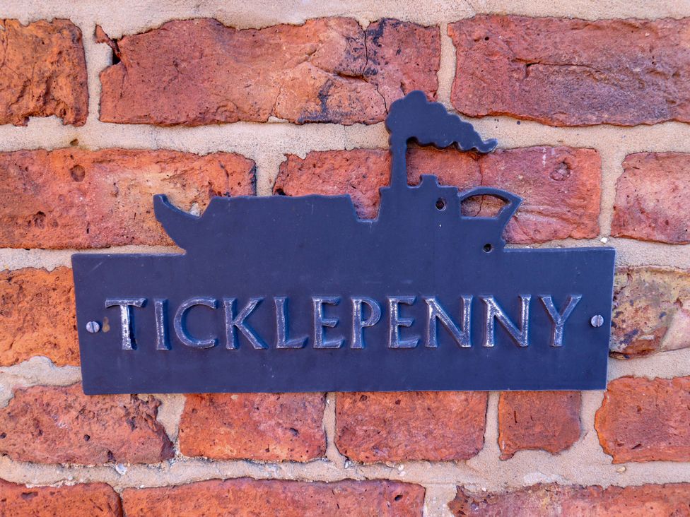 A metal sign with the text Ticklepenny attached to a brick wall at Ticklepenny in Louth
