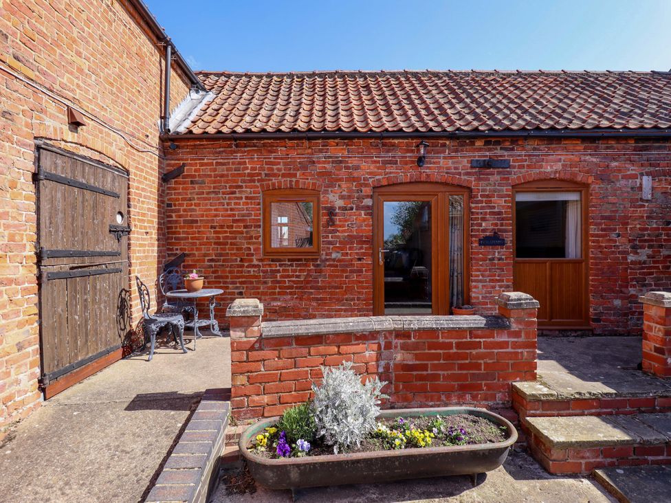 A garden area with a brick wall and furniture at Ticklepenny, Louth