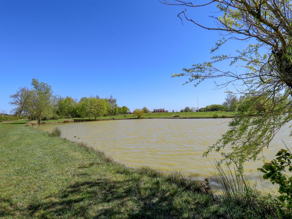 A pond with grass and trees surrounding it at Ticklepenny in Louth