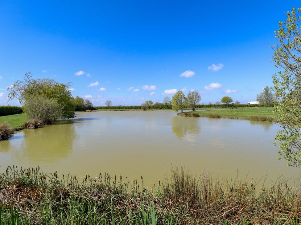 A pond surrounded by trees and grass at Ticklepenny in Louth
