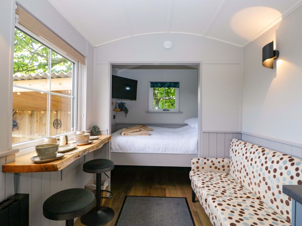 A living room with a table and chairs next to a bed at Little Hut in Grange-Over-Sands