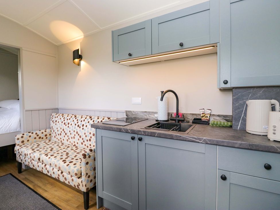 A kitchen with a sink and couch at Little Hut in Grange-Over-Sands