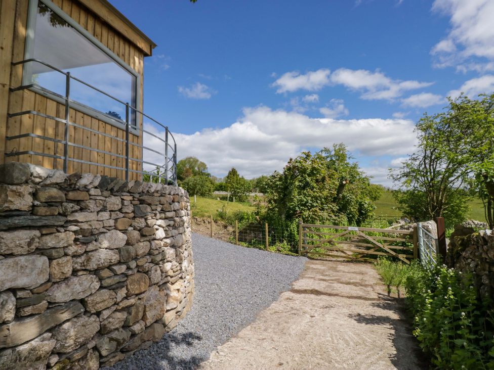 An outdoor view of a gravel driveway and gate at Little Hut in Grange-Over-Sands