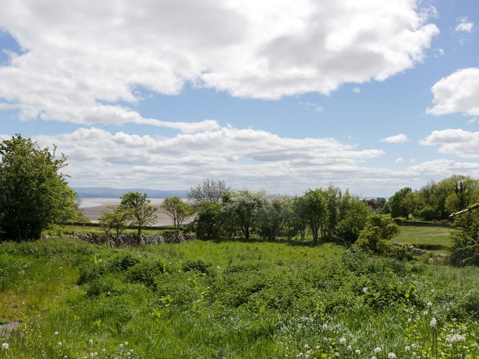 A view of trees and grass with a distant water body at Little Hut in Grange-Over-Sands