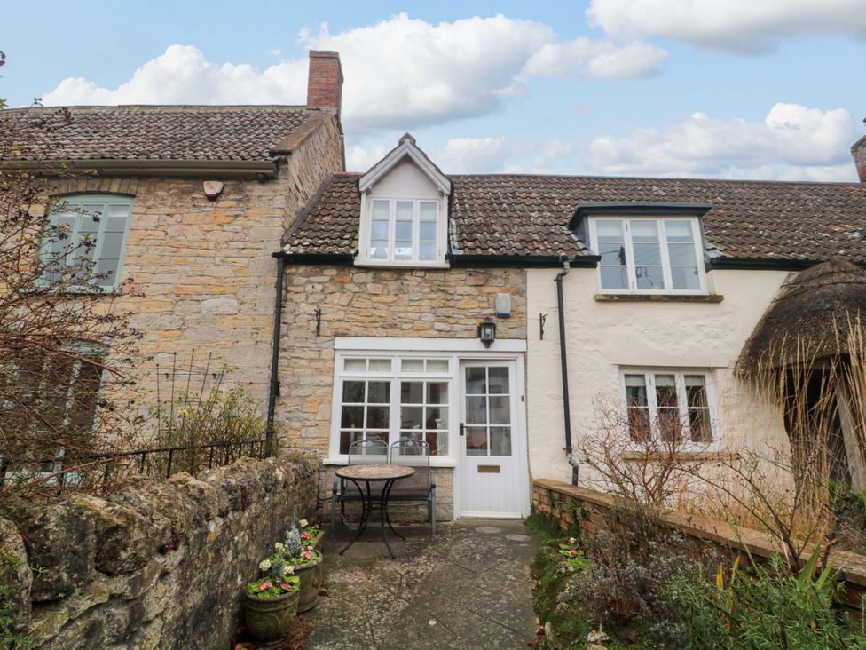 A cottage exterior with a table and chairs at Stones Bakery in Wedmore