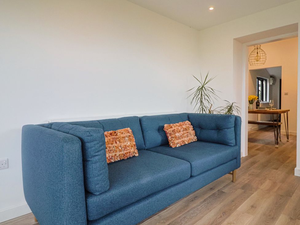 A living room with a blue sofa and a table in Little Poppes Lawn in Holditch near Hawkchurch