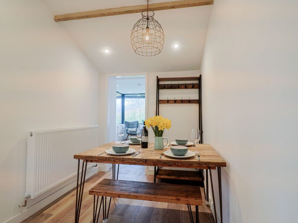 A dining room with a wooden table and flowers at Little Poppes Lawn in Holditch near Hawkchurch