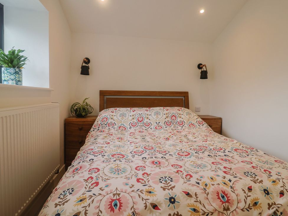A bedroom with a bed and bedside table at Little Poppes Lawn in Holditch near Hawkchurch