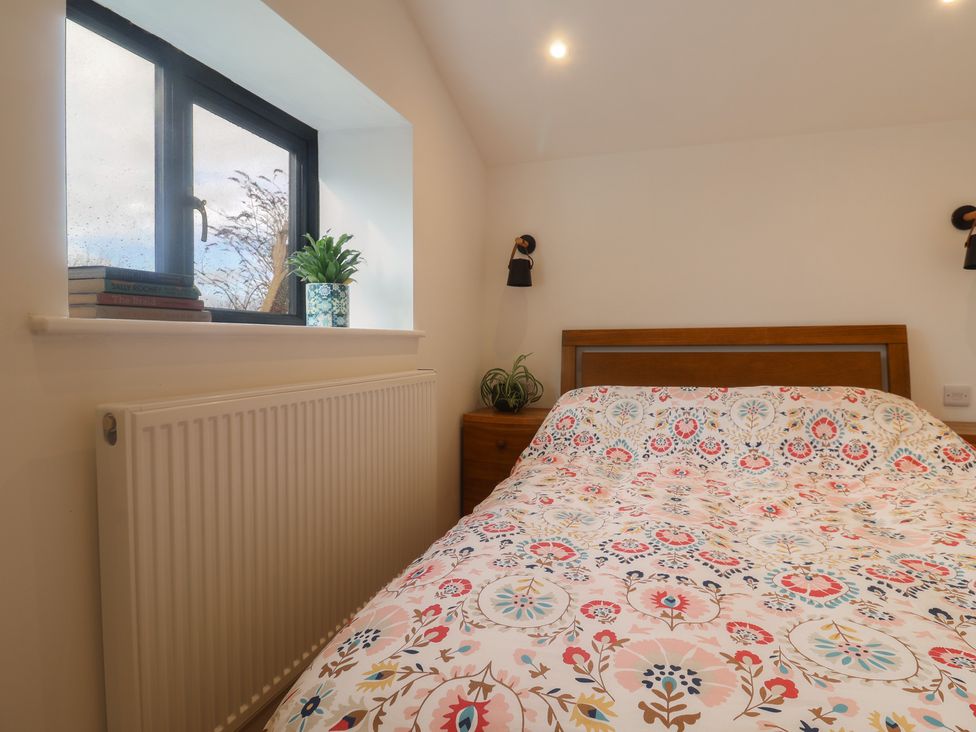 A bedroom with a bed and window at Little Poppes Lawn in Holditch near Hawkchurch