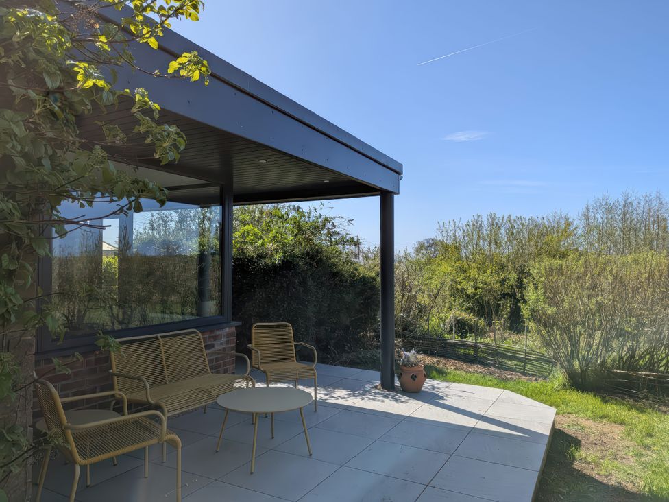 An outdoor patio with chairs and a table at Little Poppes Lawn in Holditch near Hawkchurch