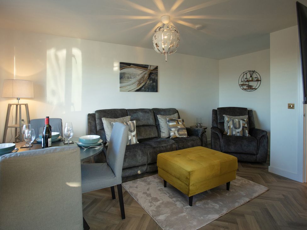 A living room with sofa, armchair, and dining table at 365 South Boisdale, Daliburgh, Isle Of South Uist