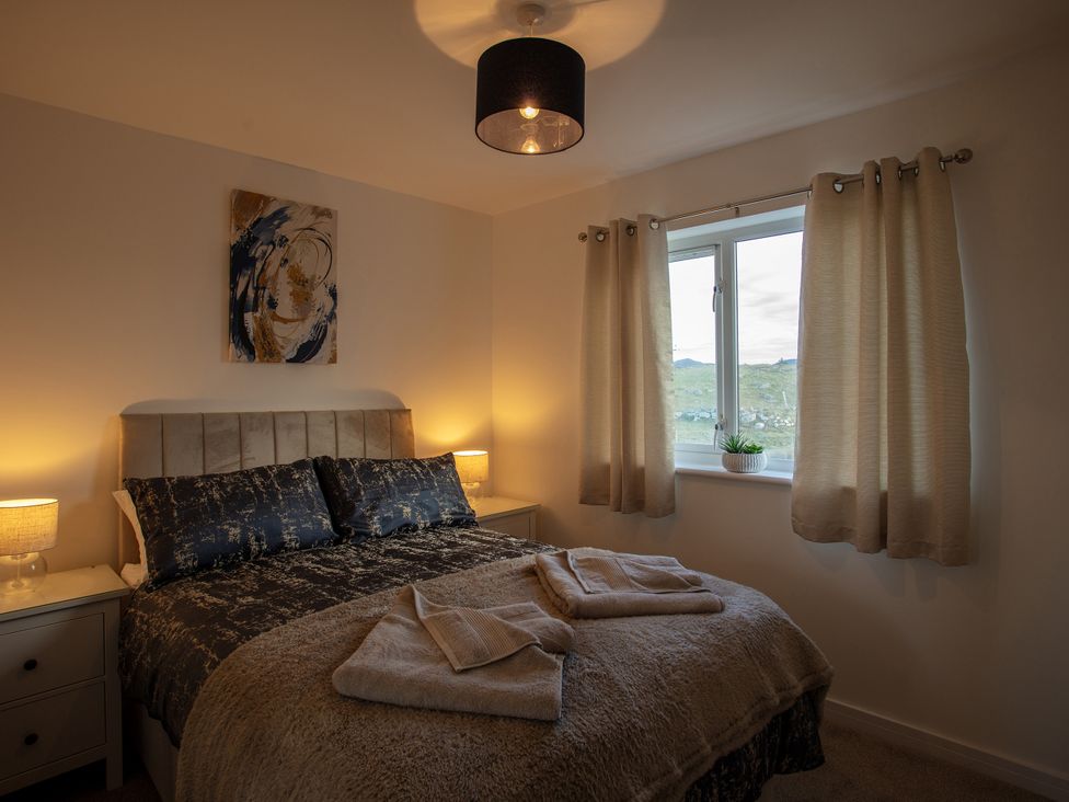 A bedroom with a bed, bedside tables, and a window at 365 South Boisdale, Daliburgh, Isle Of South Uist