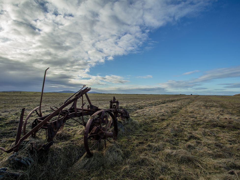 A rusty plow in an open field under a cloudy sky at 365 South Boisdale in Daliburgh, Isle Of South Uist