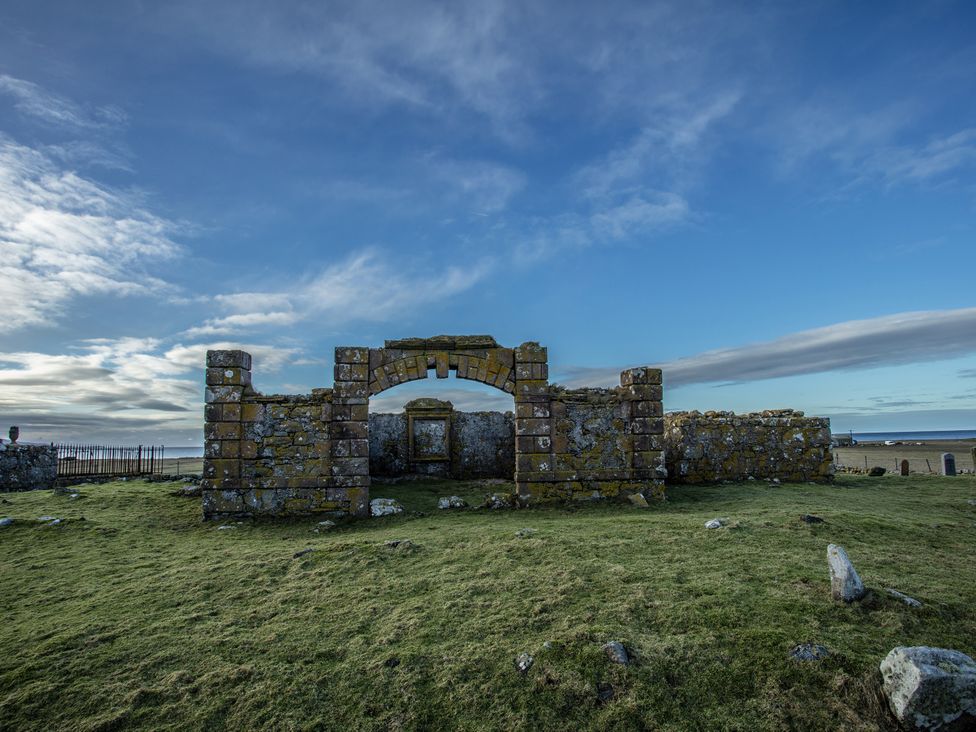Stone ruins with an archway in a grassy area at 365 South Boisdale, Daliburgh, Isle Of South Uist