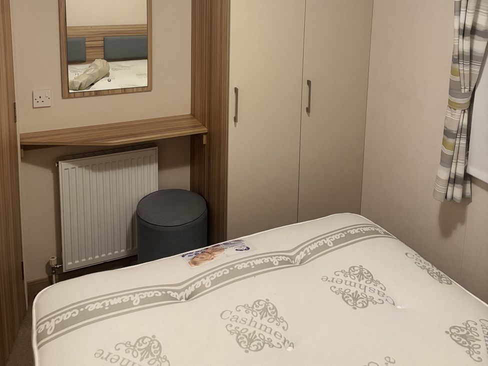 A bedroom with a bed, mirror, wardrobe, radiator, and chair at 169 Abergele